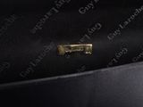 a close up of a black bag with a gold metal handle