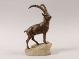 statue of a goat standing on a rock on a white background