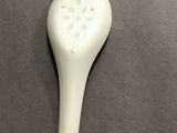 a white spoon with a flower on it on a table