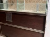 un comptoir en verre au milieu d'une pièce, avec un tableau accroché au mur derrière lui