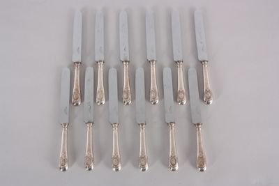 eight silverplated knives with handles and handles on a white surface
