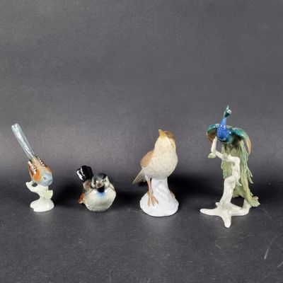 trois figurines représentant des oiseaux et une femme avec un oiseau perché sur une branche
