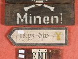 three wooden signs on the wall with a skull and crossbone on them