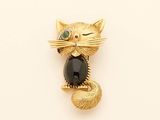 a gold cat brooch with a black stone on it