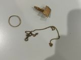 deux bagues et un collier en or posés sur une surface blanche
