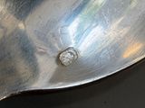 a silver spoon with a diamond on it sitting on a table