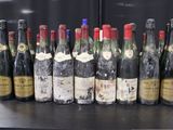 Des bouteilles de vin sont alignées sur une table devant un mur noir.