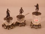 three silver figurines of men with spoons and a jar of jelly