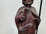 a statue of a man holding a stick and wearing a hat
