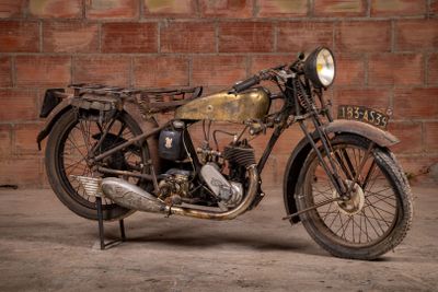 a old motorcycle that is parked in front of a brick wall