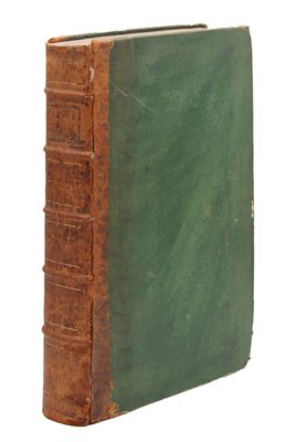 un vieux livre à la couverture verte posé sur une surface blanche