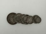 five silver coins are arranged in a row on a white surface