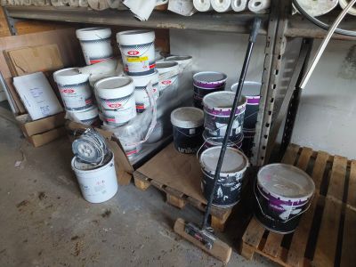 several buckets of paint are stacked on pallets in a garage