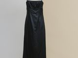 a black dress on a mannequin stand against a beige wall