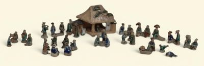 de nombreuses figurines représentant des personnes rassemblées autour d'une petite maison