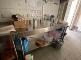 a kitchen with a large stainless steel counter and shelves