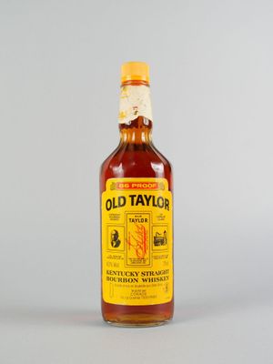 une vieille bouteille de whisky bourbon Taylor posée sur une surface blanche