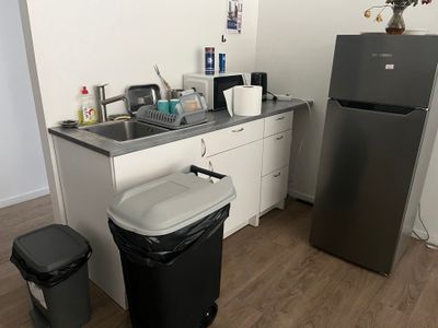 a kitchen with a refrigerator, sink, and trash can