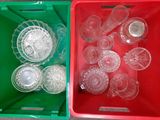 two plastic containers filled with empty glassware on a table