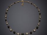 un collier noir et doré orné de perles de verre noires et blanches