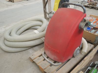 un aspirateur rouge posé sur une palette à côté d'une caisse d'outils