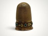 a gold thimble with blue stones on it on a white background