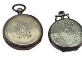 two silver pocket watches sitting side by side on a white surface