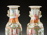 pair of chinese vases with figures on them sitting on a table