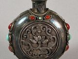 silver flask with red and green beads on a stand