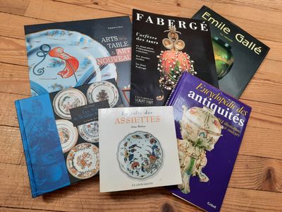 plusieurs livres posés sur une table en bois, avec un chat allongé dessus