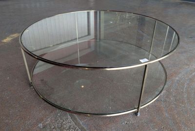 a glass coffee table with a metal base on the floor