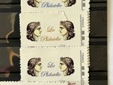 three stamps with a woman ' s face on them are on a piano keyboard