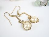earrings with pearls and gold chains on a white surface