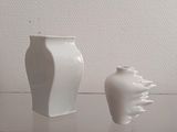 two white vases sitting on a table next to each other