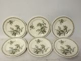 six assiettes vertes et blanches ornées d'oiseaux, posées sur une table