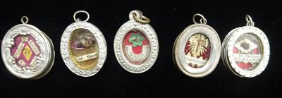 five different types of silver and enamel charms on a black background