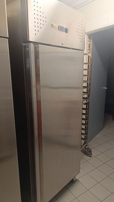 a stainless steel refrigerator in a kitchen with white tile flooring