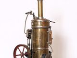 une petite machine à vapeur ancienne posée sur une étagère blanche