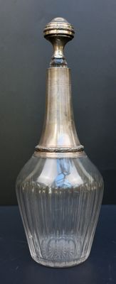 un vase en verre avec un couvercle en argent posé sur une table
