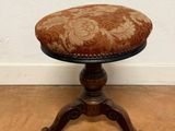un tabouret ancien en bois avec une assise rembourrée à motifs floraux
