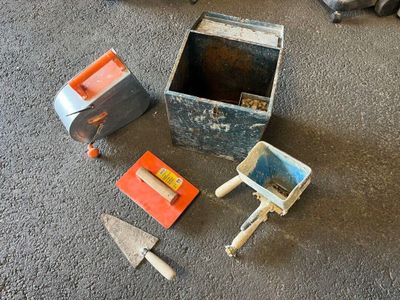 une petite boîte contenant des outils, posée par terre à côté de lui