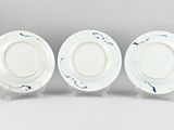 three white and blue plates on stands against a gray background