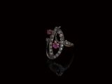 un gros plan d'une bague sertie d'un diamant et d'un rubis sur une surface noire