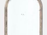 un vieux miroir au cadre blanc accroché à un mur blanc
