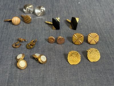 plusieurs paires de boucles d'oreilles à clous dorées et noires posées sur un tissu bleu