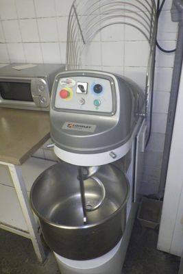 une photo d'un mixeur dans une cuisine, avec un micro-ondes en arrière-plan