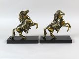 une paire de serre-livres anciens en laiton représentant des chevaux, posés sur des socles en marbre noir