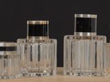trois bouteilles en verre transparent avec des bouchons noirs, posées sur une table en bois