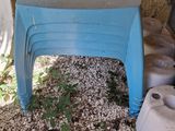 a blue plastic chair sitting next to a pile of gravel