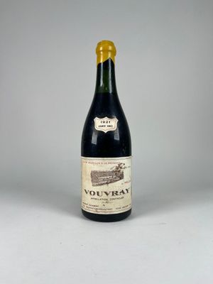 une vieille bouteille de vin posée sur une table blanche